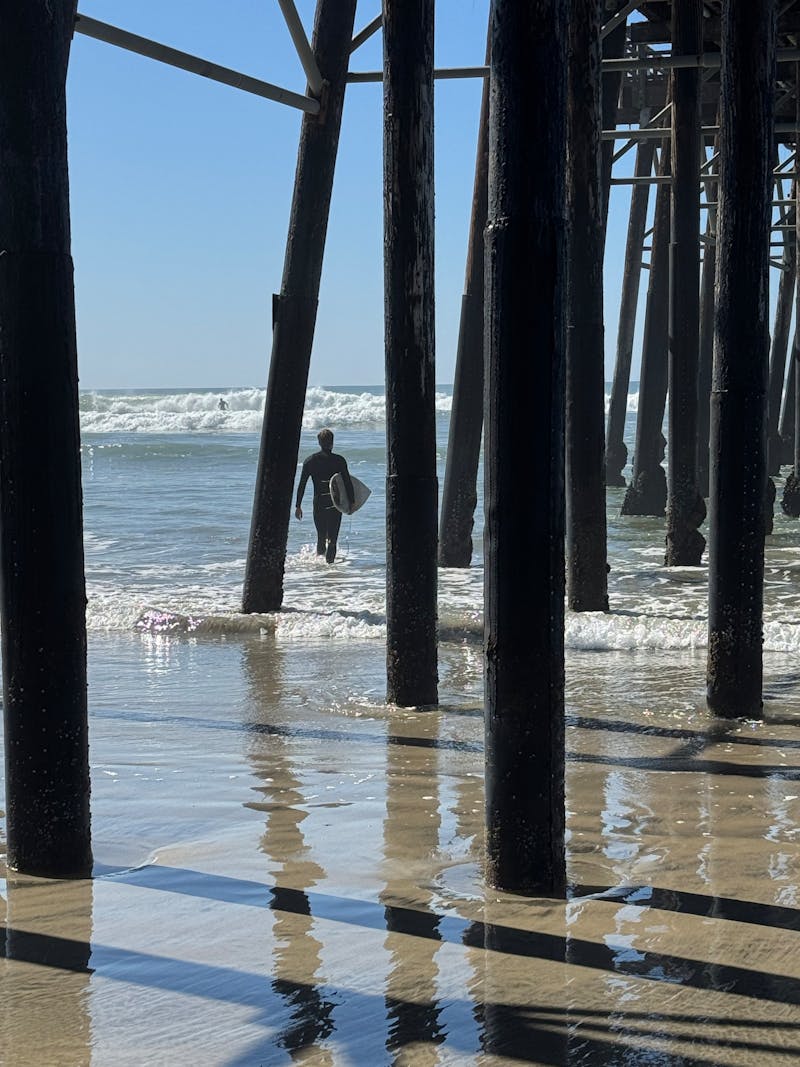 A surfer heads out at Oceanside — just 20 minutes from the property